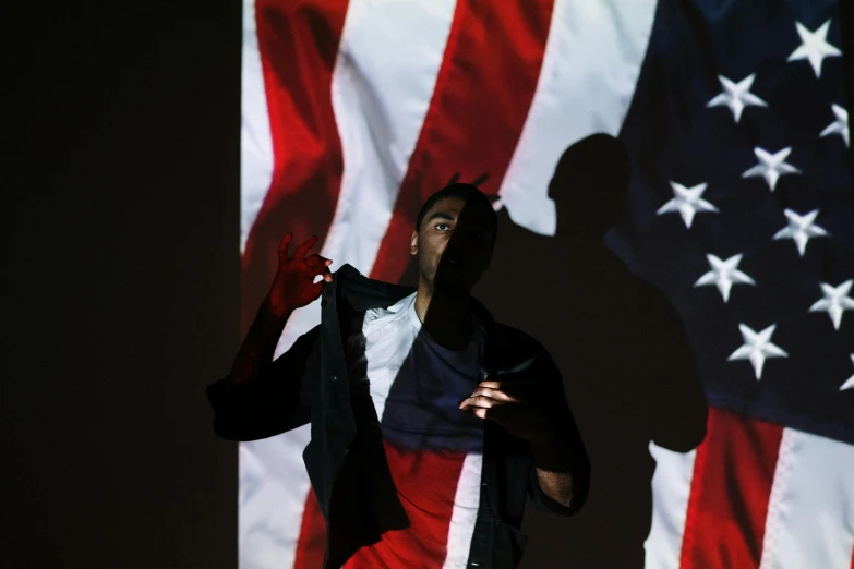 a man standing in front of an american flag, by Stokely Webster, conceptual art, 2 rappers on stage at concert, projection design installation, photograph credit: ap, jayson tatum as guerilla heroica