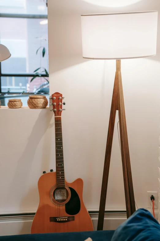 a living room filled with furniture and a guitar, by Matija Jama, trending on pexels, light and space, standing lamp luxury, light from bottom, wood accents, front lit