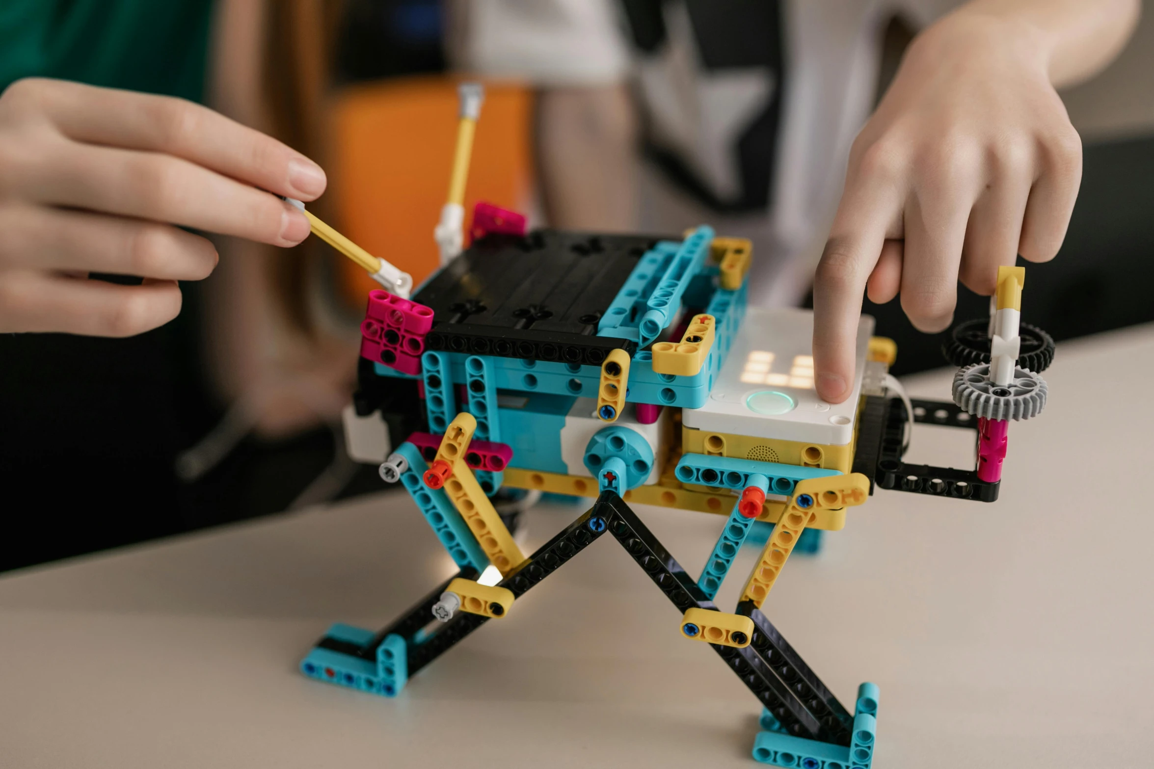 a child playing with a robot made of legos, pexels contest winner, mechanical spider legs, cyan, school class, multicoloured