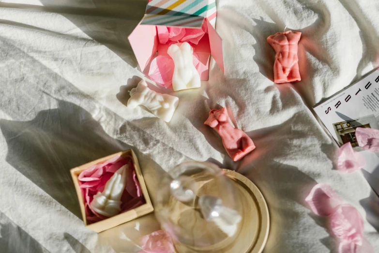 a box of soap sitting on top of a bed, a marble sculpture, inspired by Rachel Whiteread, pexels contest winner, figuration libre, gumdrop bunnies, floating in perfume, covered with pink marzipan, overview