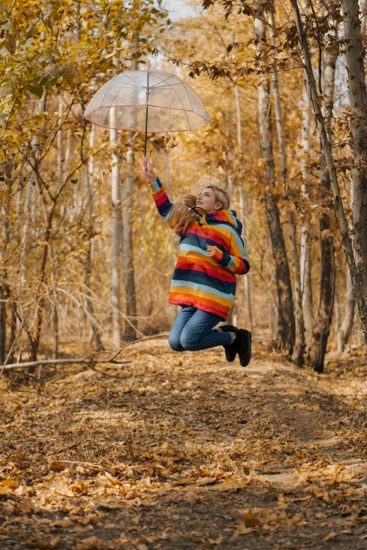 a person jumping in the air with an umbrella, inspired by Jan Rustem, pexels contest winner, sitting in the forrest, wearing a colorful coogi sweater, a blond, lesbians