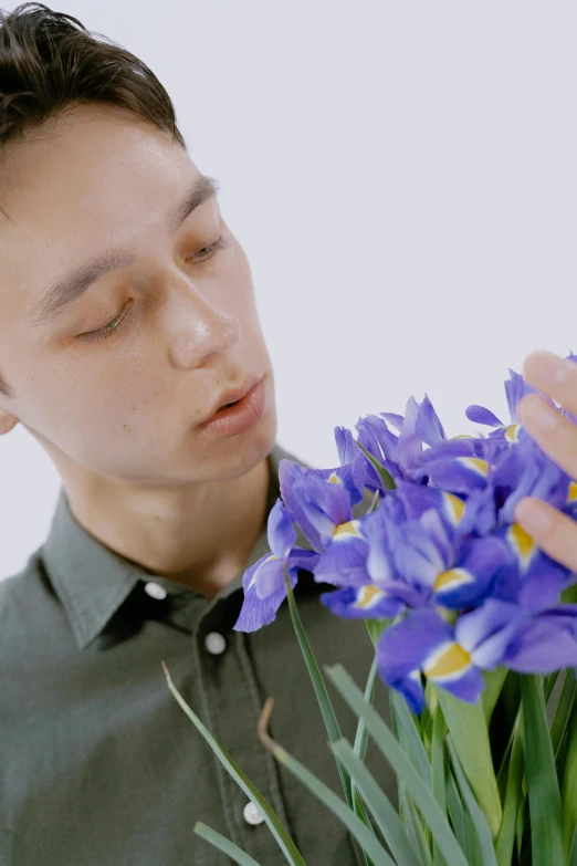 a man holding a bunch of purple flowers, an album cover, inspired by Jean Malouel, hyperrealism, low quality video, iris compiet, ignant, taken with sony alpha 9