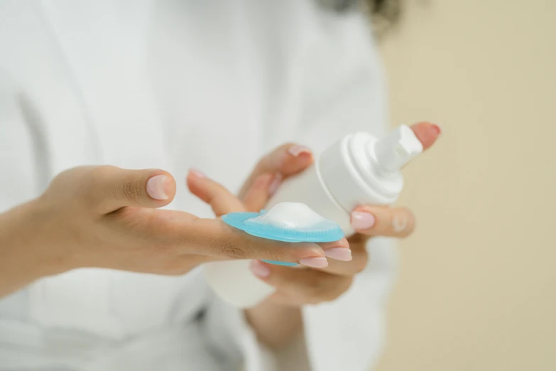 a close up of a person holding a bottle of liquid, cream, avatar image, petite, blue