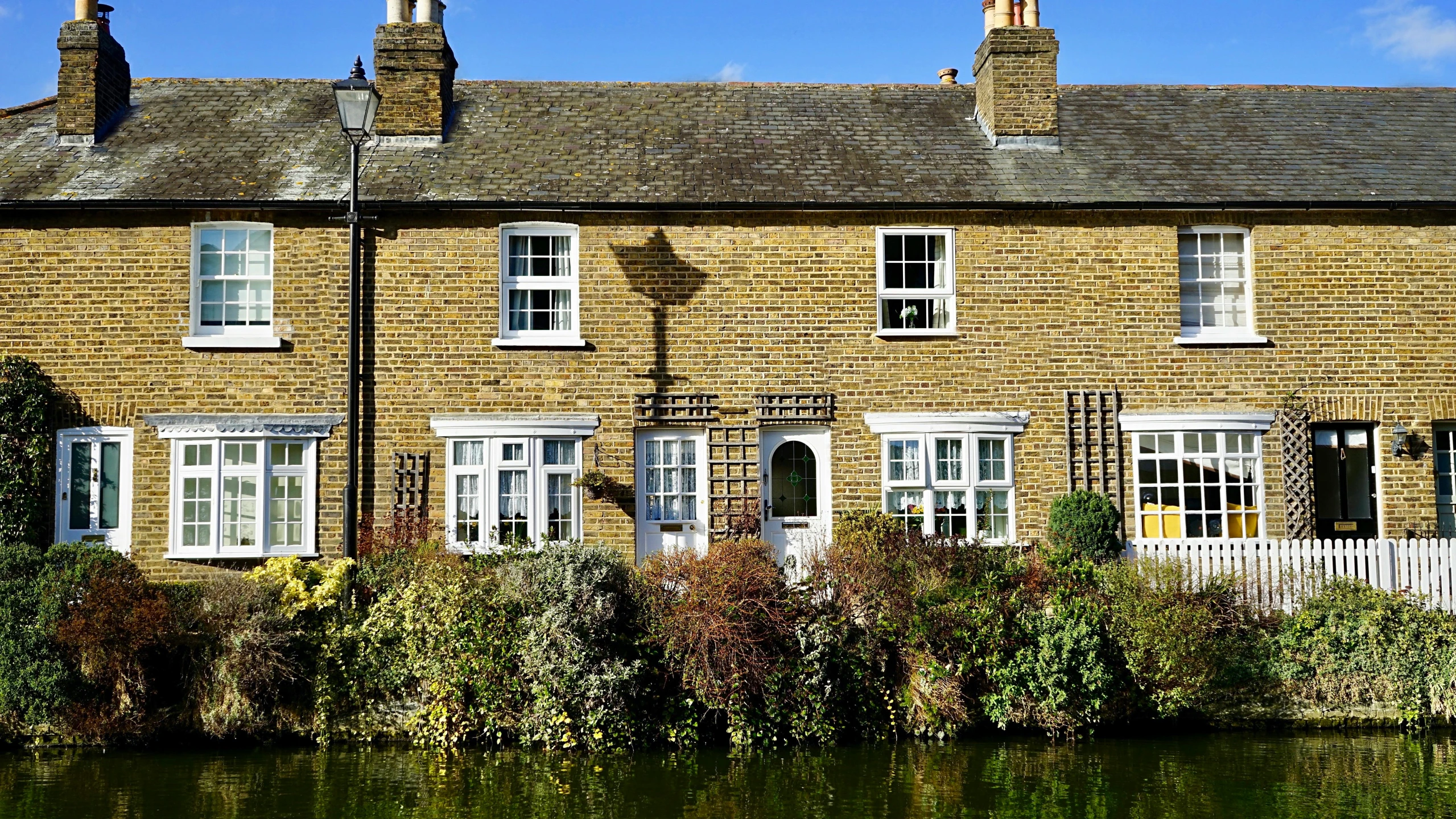 a row of houses next to a body of water, by Carey Morris, pixabay, arts and crafts movement, golden windows, an estate agent listing photo, canals, 2 0 0 0's photo