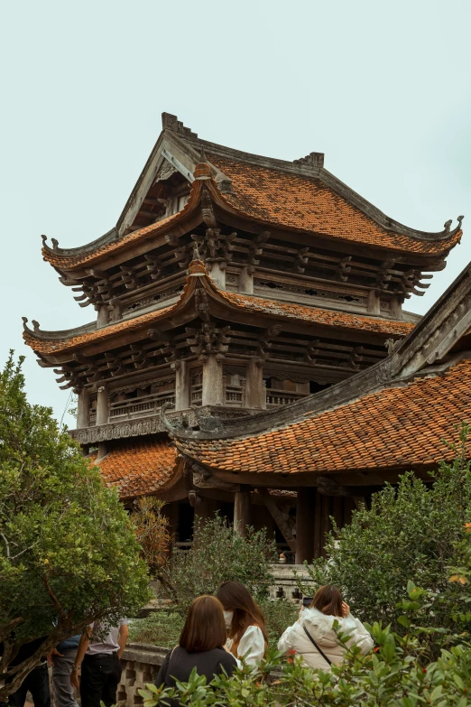 a group of people standing in front of a building, an album cover, inspired by Hu Zao, trending on unsplash, tiled roofs, vietnam, monastery, large overhangs