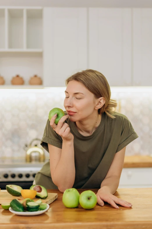 a woman sitting at a kitchen table eating an apple, trending on pexels, avacado dream, soft chin, profile image, kiwi