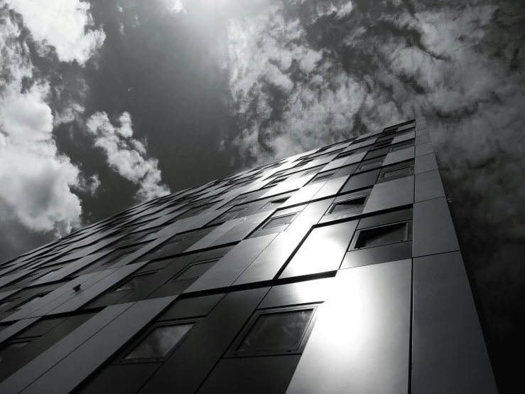 a black and white photo of a tall building, inspired by Richard Wilson, pexels contest winner, light and space, metal cladding wall, cumulus, solarised, seen from outside