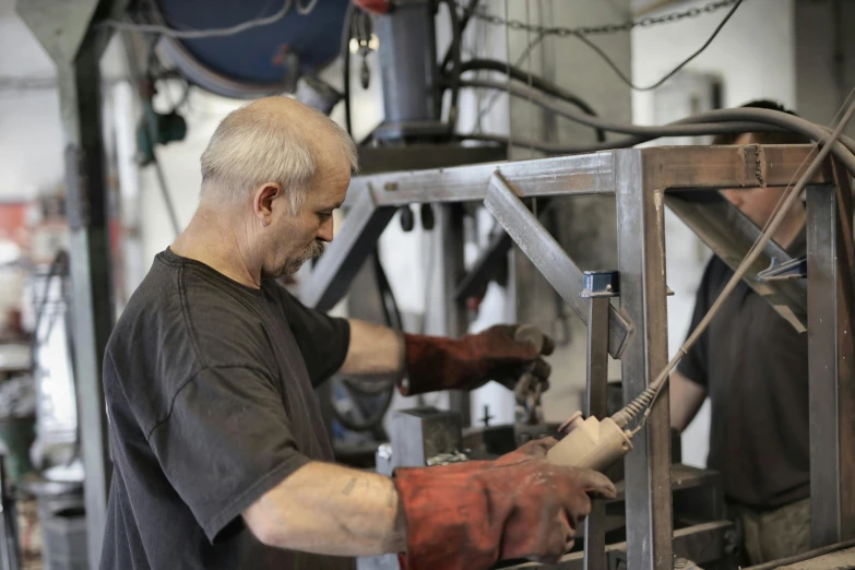 a man working on a machine in a factory, arbeitsrat für kunst, hinged titanium legs, 🦑 design, white metal, avatar image