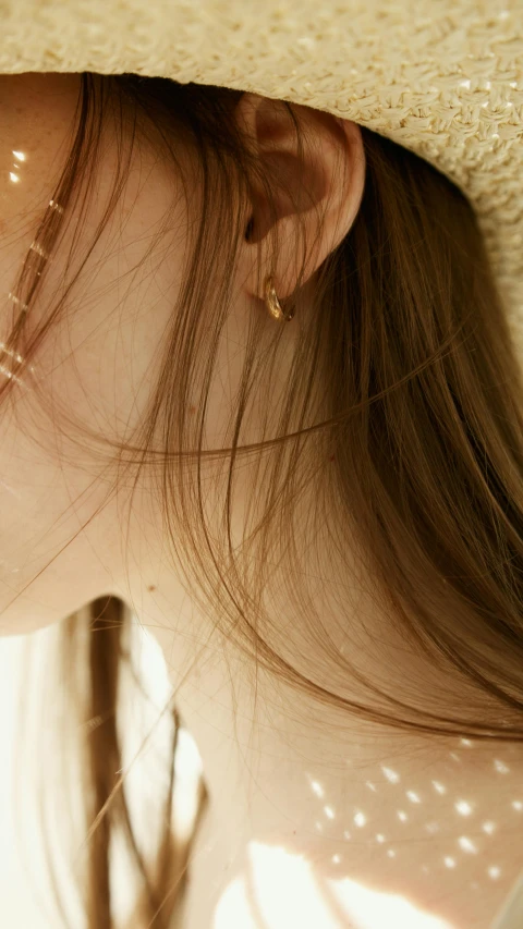 a close up of a person wearing a hat, gold earring, eeri, 8 k ), super detailed image