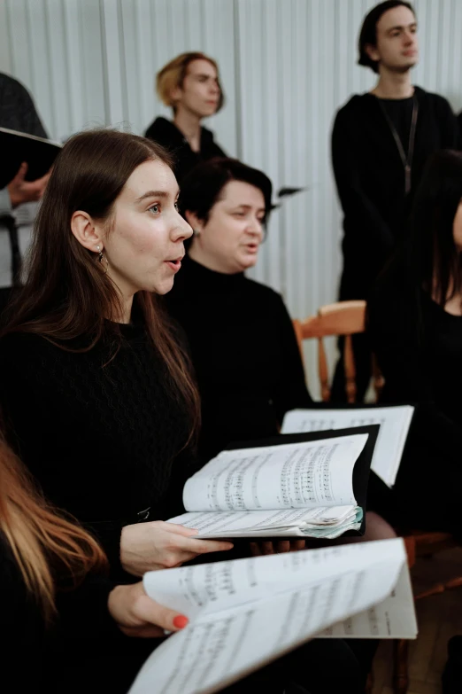 a group of people in a room with sheet music, by Attila Meszlenyi, reddit, choir, high quality photo, woman in black robes, highly focused