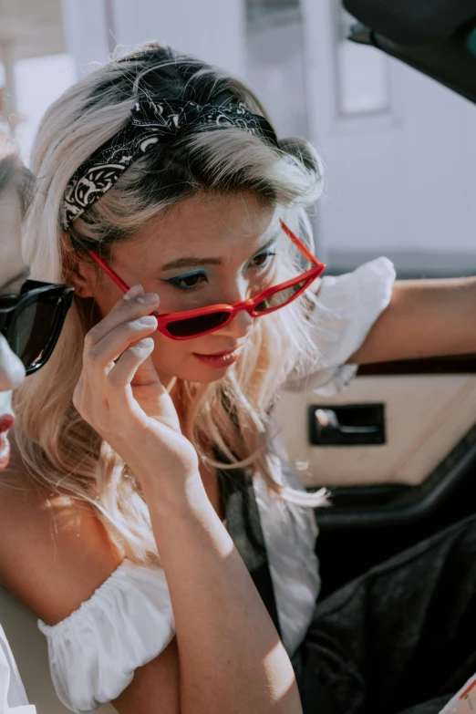 a woman sitting in a car talking on a cell phone, inspired by Sydney Carline, rococo, red sunglasses, profile image, kombi, at a fashion shoot