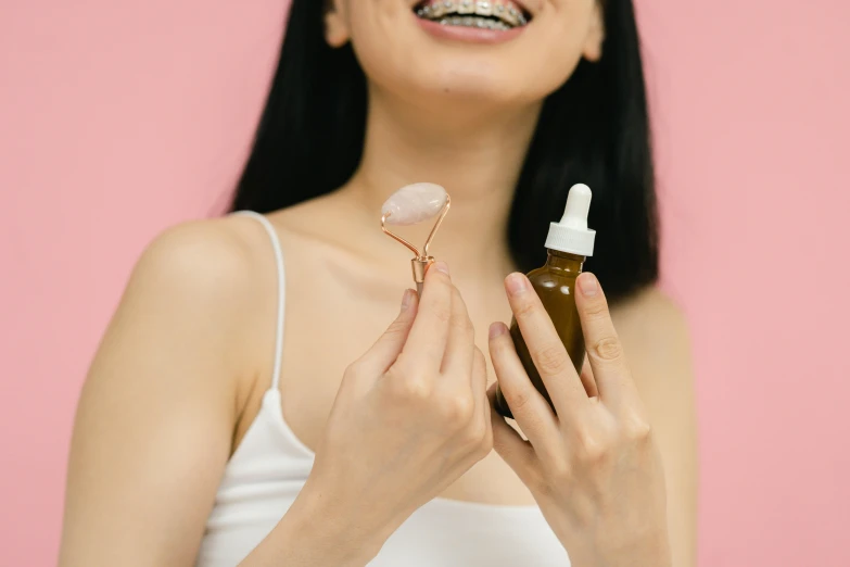 a close up of a person holding a bottle of liquid, by Julia Pishtar, trending on pexels, antipodeans, big smile on her face, diamond and rose quartz, candy treatments, asian female