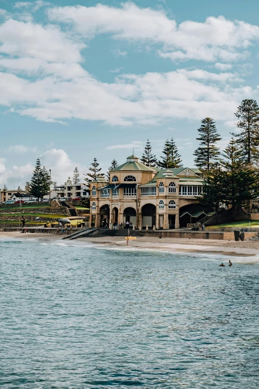 a building sitting on top of a beach next to a body of water, renaissance, victoriana, near the beach, high arches, bathhouse