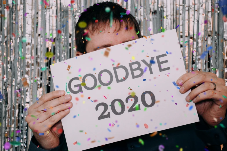 a man holding a sign that says goodbye 2020, a photo, trending on pexels, confetti, 2 0 2 5 popstar comeback single, facepalm, instax