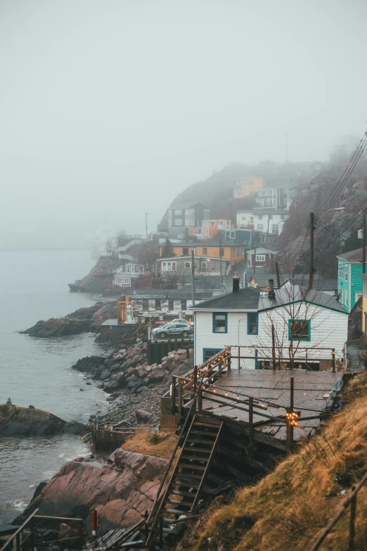 a group of houses sitting on top of a hill next to a body of water, inspired by Elsa Bleda, pexels contest winner, visual art, raging sea foggy, canada, small port village, colorful scene