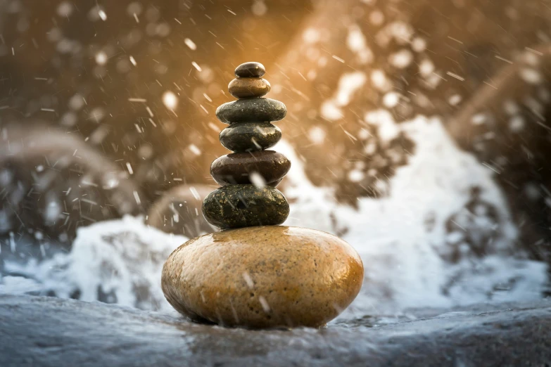 a stack of rocks sitting on top of a body of water, an album cover, unsplash, realism, rain splashing, hindu stages of meditation, 9 9 designs, balancing the equation