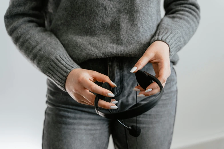 a close up of a person holding a cell phone, by Nina Hamnett, happening, headphone stand, black, smallest waistline, closeup - view