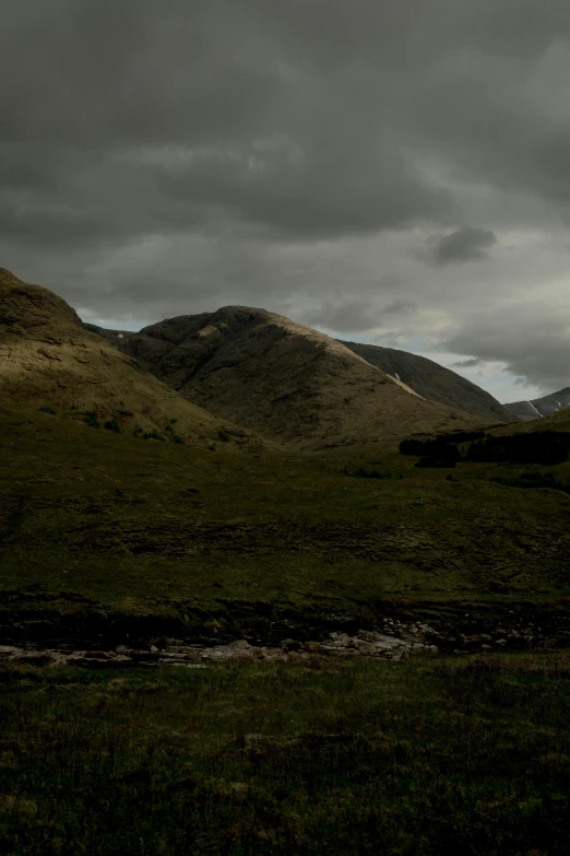 a couple of horses standing on top of a lush green field, a matte painting, unsplash, hurufiyya, scottish highlands, gloomy lighting!!!, scenic view at night, rocky hills