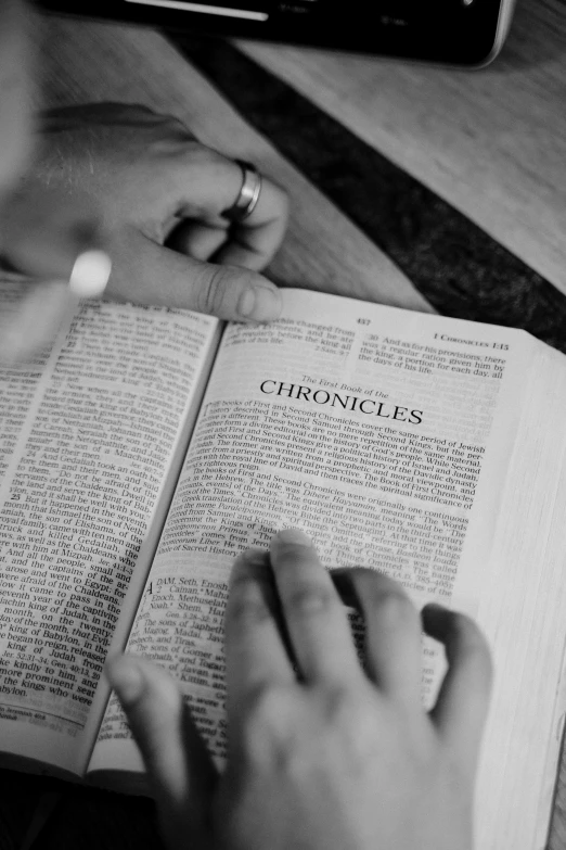 a black and white photo of a person reading a book, by Sam Charles, prophecy, [ cinematic, bible, chrome hearts