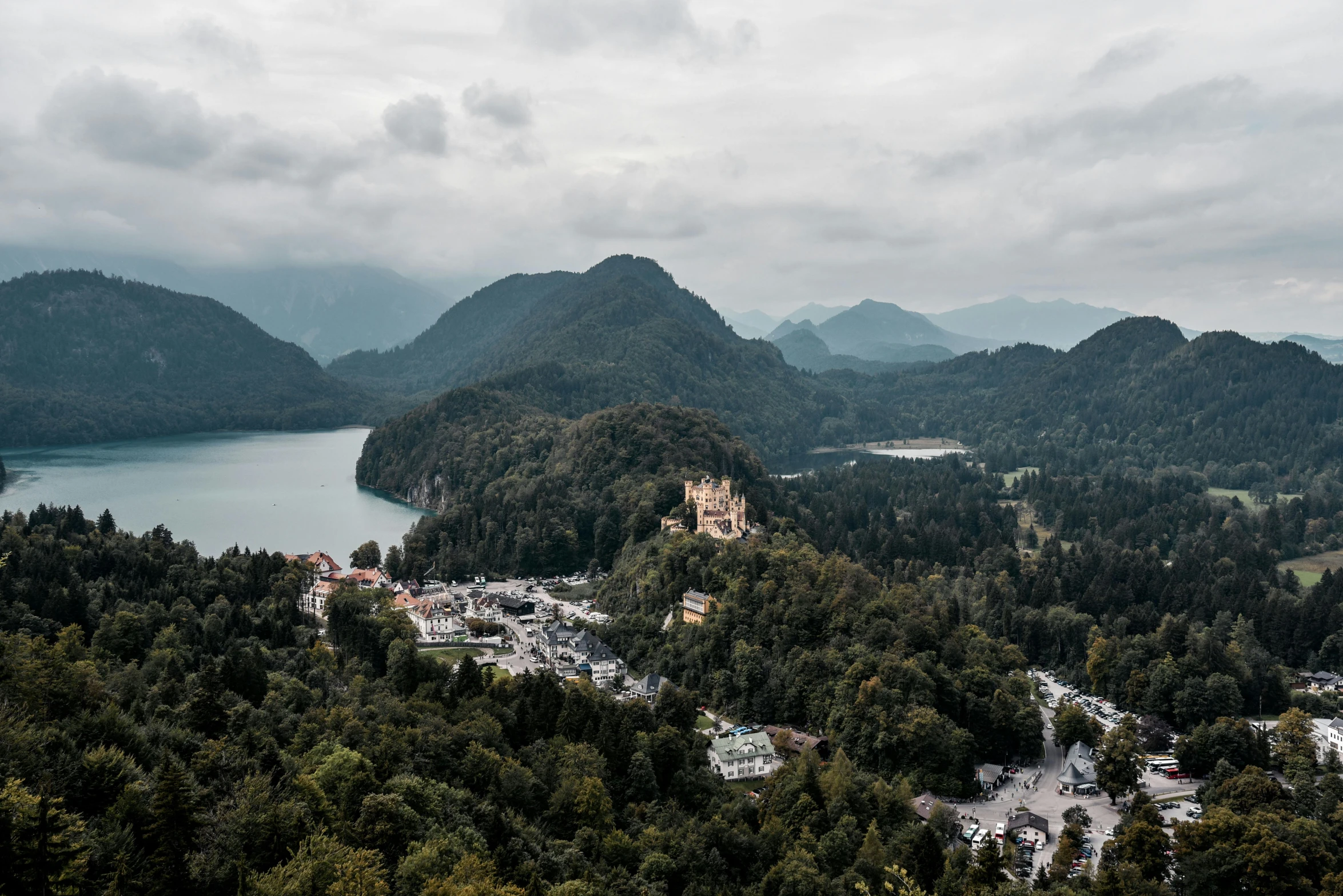 a castle sitting on top of a lush green hillside, by Sebastian Spreng, unsplash contest winner, mountains and lakes, city buildings on top of trees, high view, 2 0 0 0's photo