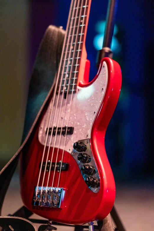 a red guitar sitting on top of a guitar stand, bassist, zoomed in, tournament, promo image