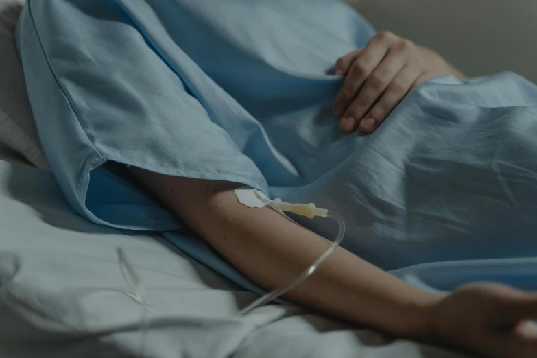 a close up of a person laying in a hospital bed, gown, plated arm, background image