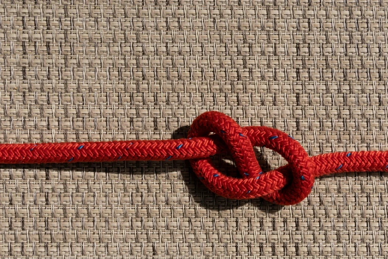 a red rope with a knot on it, by Kazimierz Wojniakowski, pexels, sōsaku hanga, stitched together, rectangular, symmetric detailed, sheath