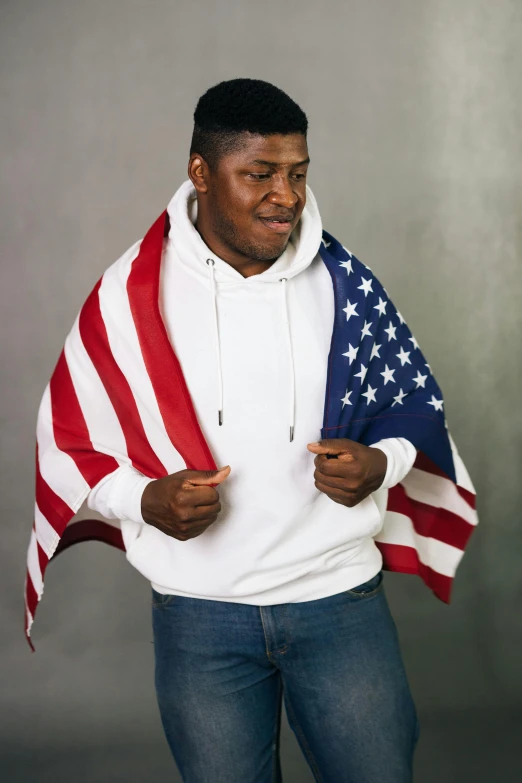 a man in a white hoodie holding an american flag, huell babineaux, model posing, in 2 0 1 5, promo image