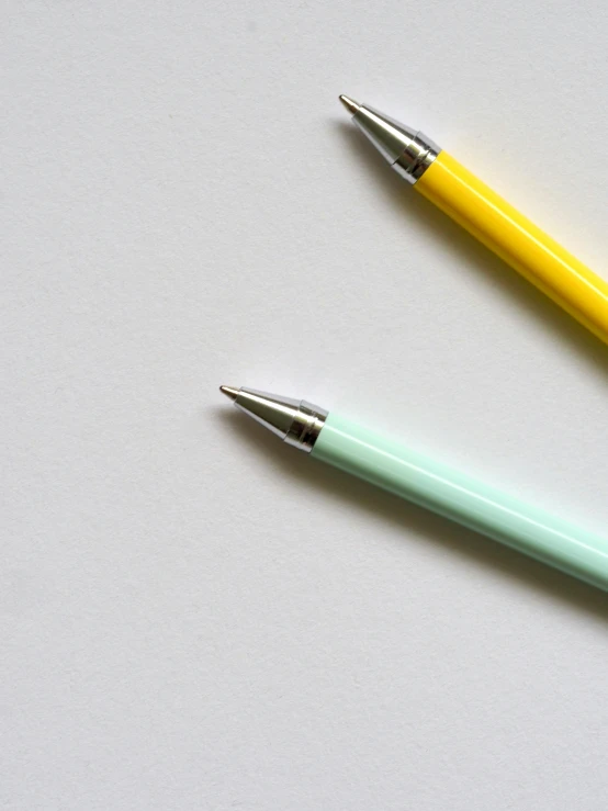 two pens sitting next to each other on a table, by Carey Morris, minimalism, yellow and green, mint, schools, close-up product photo