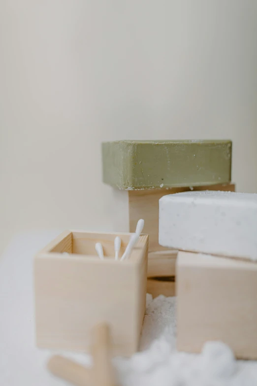 a couple of boxes sitting on top of a snow covered ground, inspired by Rachel Whiteread, unsplash, olive green, soap, wall, beige