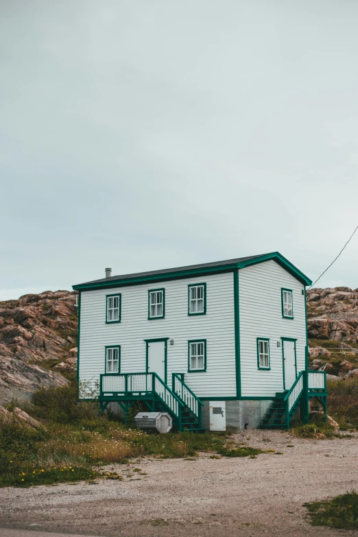 a white house sitting on the side of a road, inuit heritage, sea - green and white clothes, high quality photo, exterior photo