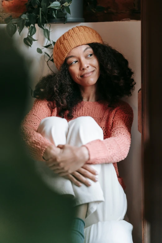 a woman holding a baby in her arms, pexels contest winner, long orange sweatshirt, tessa thompson inspired, wearing wool hat, at home