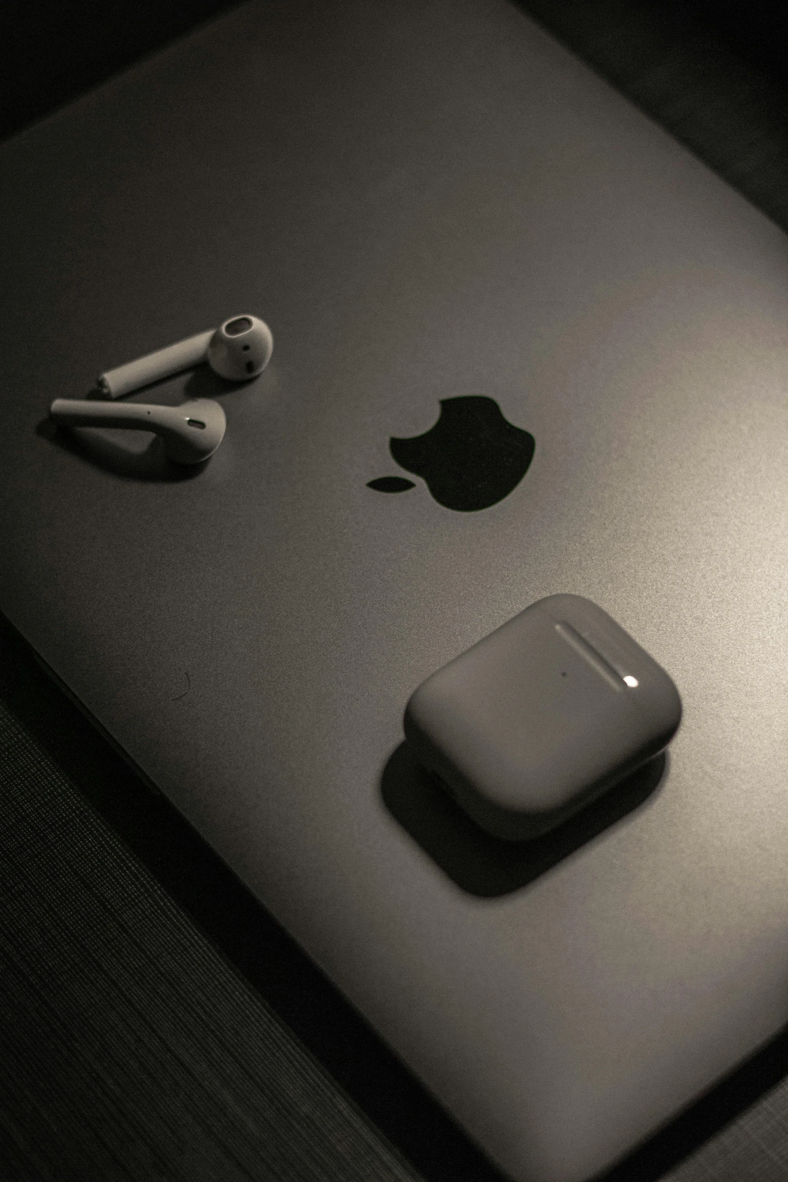 a laptop computer sitting on top of a wooden table, airpods, black on black, thumbnail, high-angle