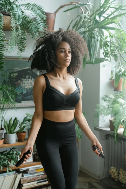 a woman standing in front of a window holding a tennis racquet, inspired by Daphne Allen, happening, wearing a crop top, all black matte product, filled with plants, heart rate