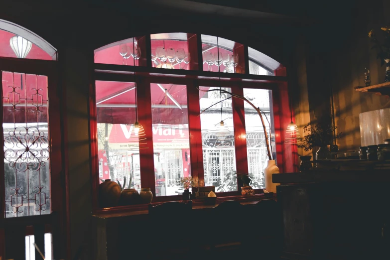 a person sitting at a table in front of a window, by Sebastian Vrancx, pexels contest winner, art nouveau, red curtain, inside a bar, view from front, shop front