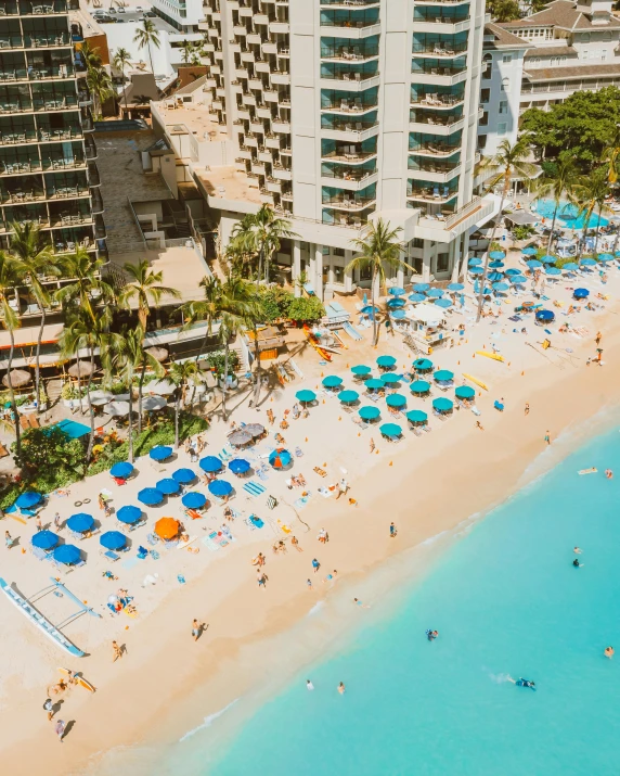 a beach filled with lots of blue umbrellas next to tall buildings, posing in waikiki, bird's view, swim suite, instagram story