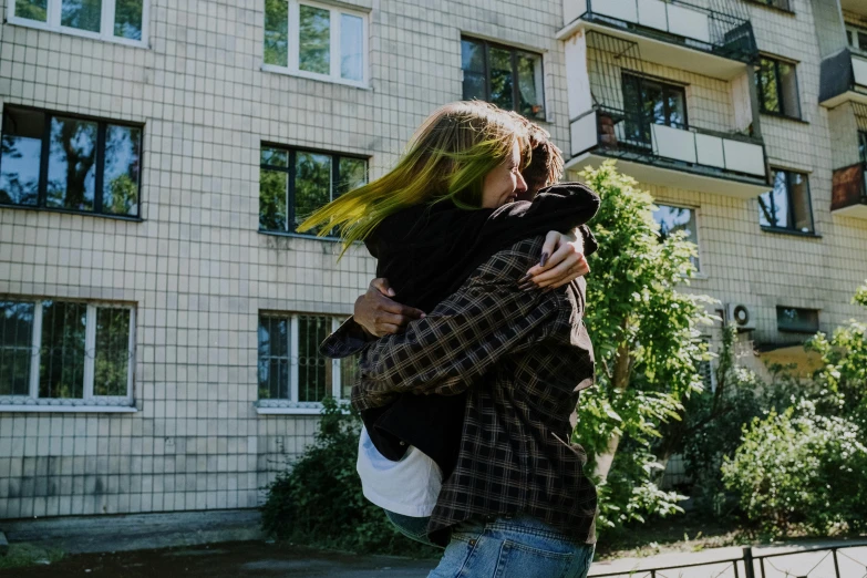 a man and a woman hugging each other in front of a building, pexels contest winner, happening, russian girlfriend, non-binary, teenage girl, in a suburb