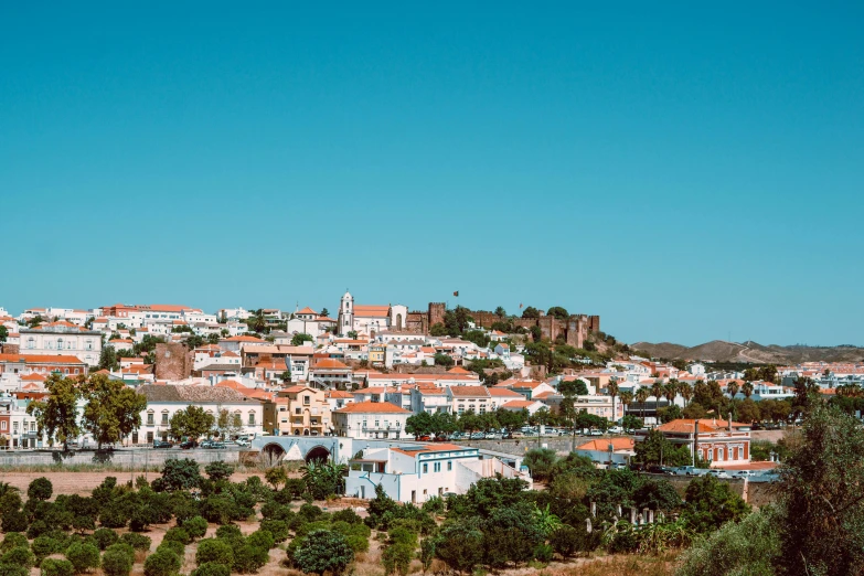 a view of a town from the top of a hill, by Alexis Grimou, pexels contest winner, white buildings with red roofs, clear blue skies, metallic, 2000s photo