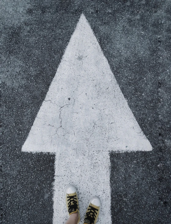 a person standing in front of a white arrow, trending on unsplash, concrete art, christmas tree, paved, begging, ( ( photograph ) )