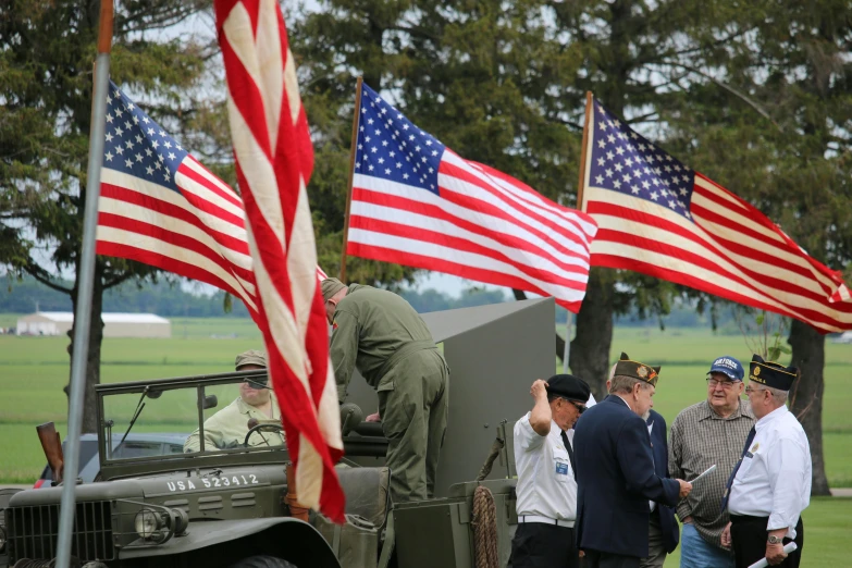 a group of men standing around a military vehicle, a photo, by David Simpson, flickr, american flags, historically accurate, banner, close up shot from the side