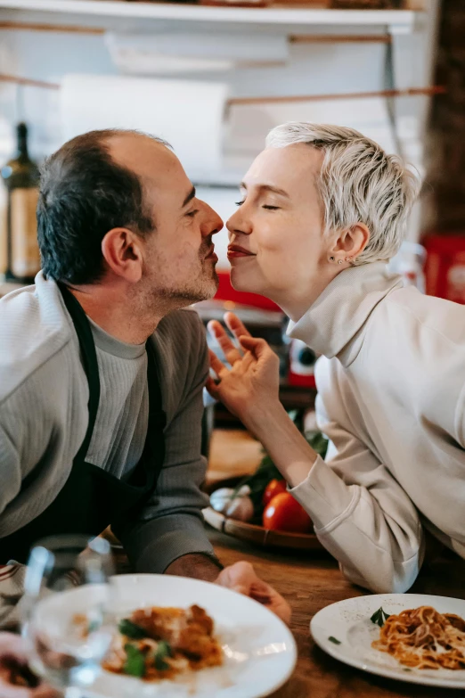 a man kissing a woman over a plate of food, pexels contest winner, short grey hair, on kitchen table, non binary model, gif