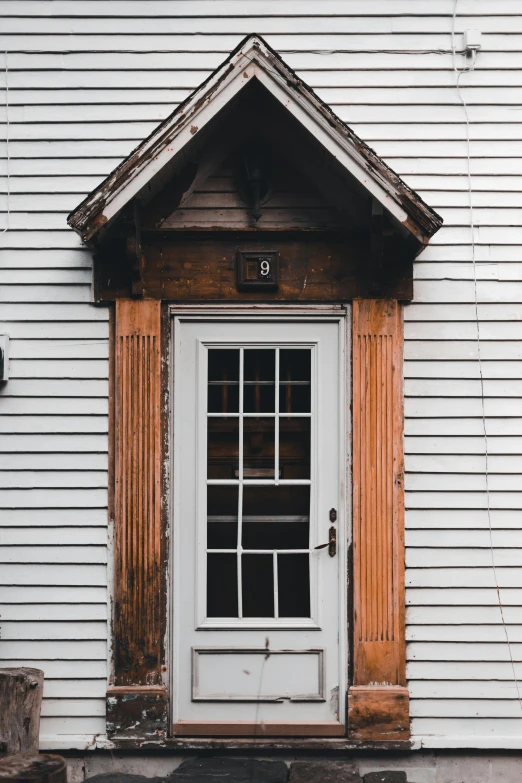 a white door sitting on the side of a white house, by Robert Storm Petersen, pexels contest winner, reclaimed lumber, ivory and copper, bay window, 1759