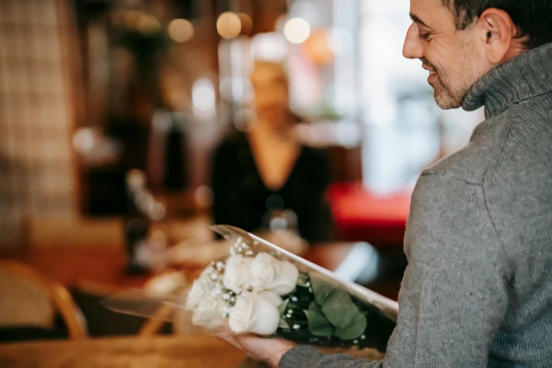 a man holding a bunch of white flowers, pexels contest winner, standing in a restaurant, inspect in inventory image, romantic, carrying a tray