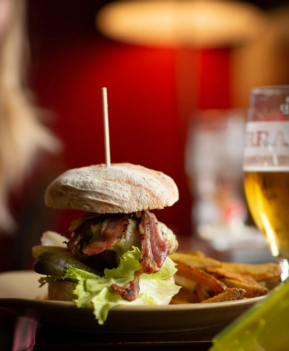 a sandwich sitting on top of a plate next to a glass of beer, profile image, glasgow, red stripe, serving burgers