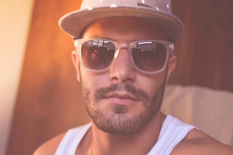 a close up of a man wearing sunglasses and a hat, trending on pexels, gradient brown to white, short stubble, aboriginal australian hipster, young greek man