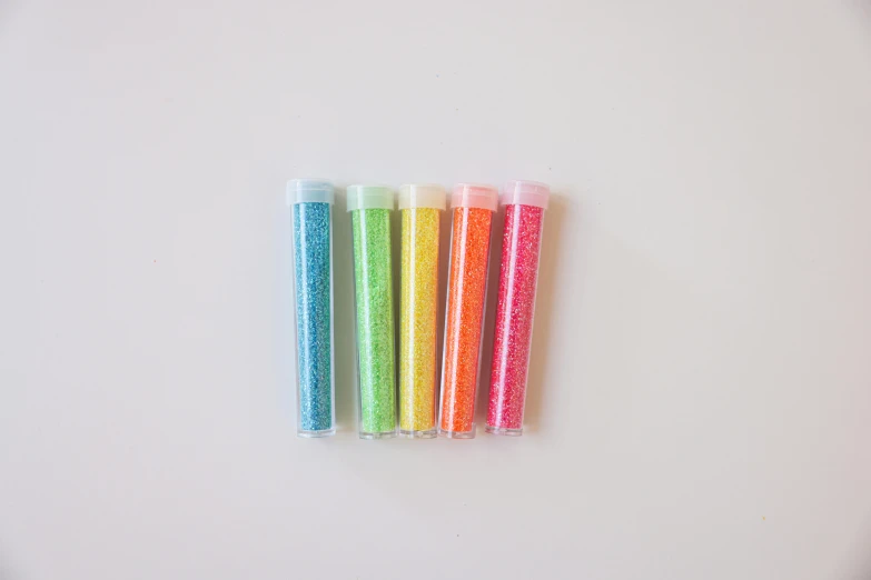 a group of toothbrushes sitting on top of a white surface, a stipple, inspired by Damien Hirst, kinetic pointillism, chartreuse and orange and cyan, :6 smoke grenades, glitter gif, miniature product photo