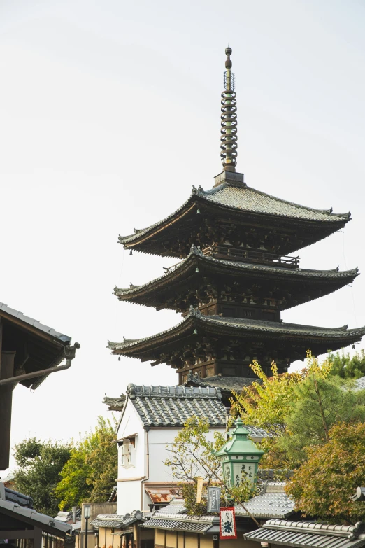 a group of people walking down a street in front of a pagoda, inspired by Kanō Shōsenin, trending on unsplash, shin hanga, roof with vegetation, two organic looking towers, high detail photo, seen from outside