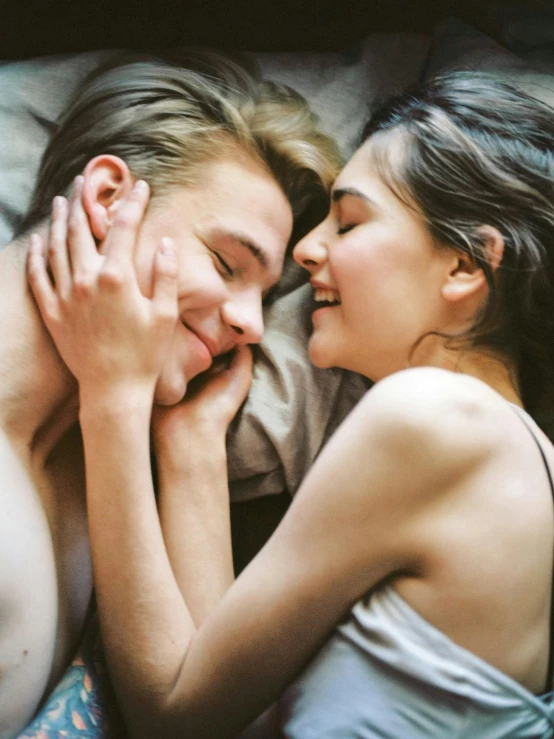 a man and woman laying in bed next to each other, a picture, trending on pexels, grinning lasciviously, two men hugging, 🤬 🤮 💕 🎀, high angle close up shot