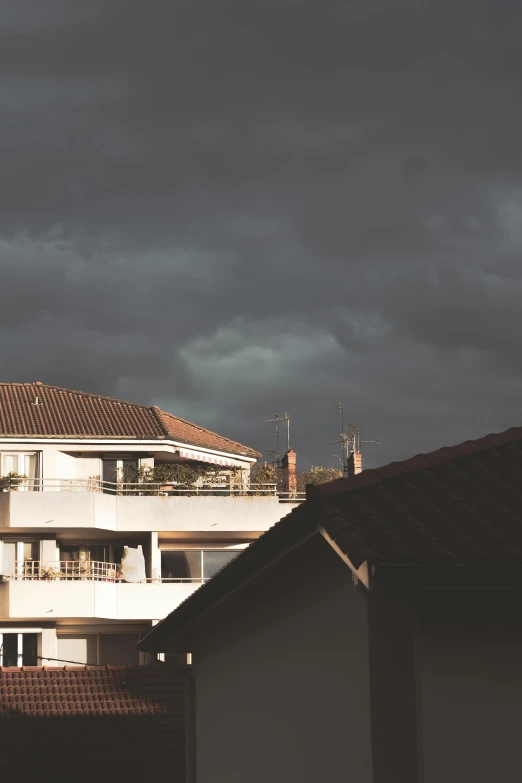 a clock tower on top of a building under a cloudy sky, a colorized photo, by Alexis Grimou, renaissance, thunderstorms, residential area, late afternoon light, roof with vegetation