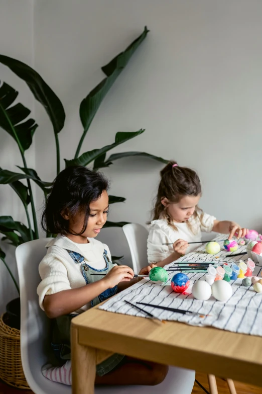 a couple of kids that are sitting at a table, inspired by Pacita Abad, pexels contest winner, eggshell color, decorations, weaving, plants